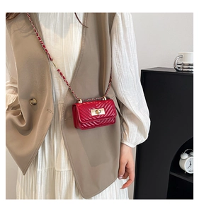 Detail of red quilted mini crossbody bag featuring a golden twist lock and chain strap