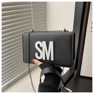 Detail of black crossbody bag with white SM metal logo and silver chain strap