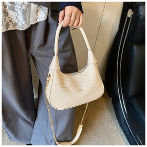 Detailed close-up of cream woven shoulder bag with chain strap and embossed logo
