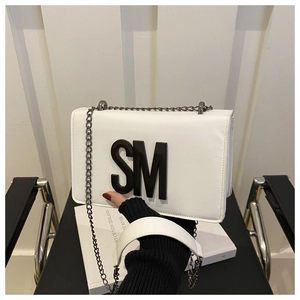 Close-up of white leather crossbody bag with black SM letter and metal chain strap