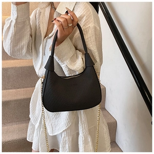 Detail of black textured crescent bag with gold chain and woven leather finish