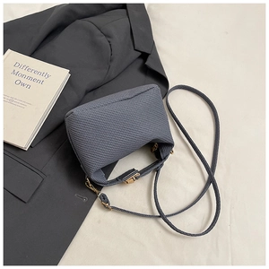 Détail du sac en tissu texturé gris foncé sur blazer avec ferrures dorées en métal