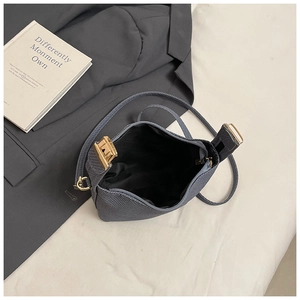 Vue détaillée d'un sac polochon en cuir gris foncé montrant la fermeture dorée et l'intérieur