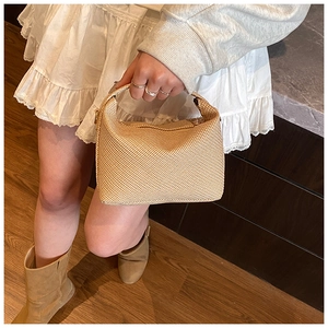 Détail du sac polochon tissé avec texture à micro-carreaux beige et poignée