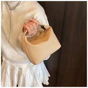 Détail du tissage du mini sac à main kaki clair avec fermoirs dorés porté par un mannequin
