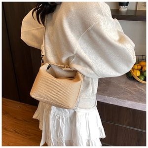 Detail van beige geweven crossbodytas met gouden gesp getoond op een vrouwelijk model