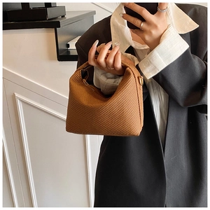 Gros plan sur la texture tressée marron et la poignée incurvée de ce sac hobo chic