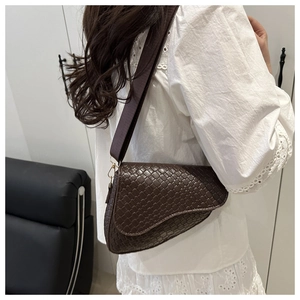 Detailed view of dark brown saddle bag with premium woven texture and wide strap
