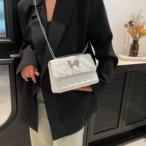 Chic white quilted crossbody bag with silver butterfly buckle and chain strap on a model