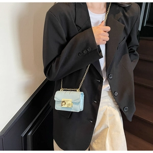 Détail d'un mini sac bandoulière bleu ciel avec boucle dorée porté sur une veste noire