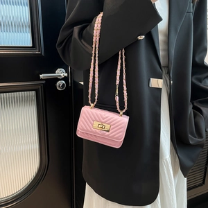 Chic pink quilted mini crossbody bag with gold chain strap worn over a black blazer