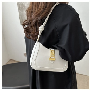Détail d'un sac sous le bras blanc en forme de croissant avec boucle dorée et nœud
