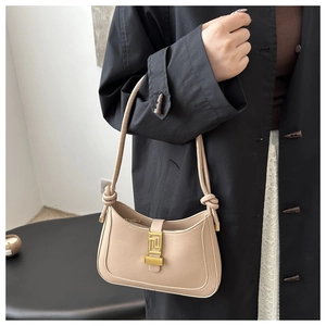 Dettaglio della borsa a spalla in ecopelle beige con fibbia dorata e nodi sulla tracolla