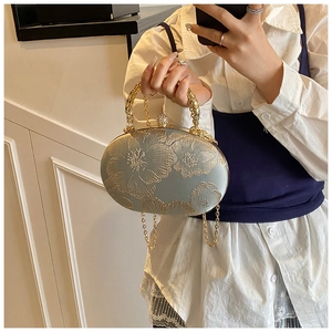 Mirror selfie showing the vintage light blue satin evening bag with floral embroidery