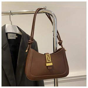 Dettaglio borsa a spalla in pelle marrone scuro con fibbia dorata e tracolla con nodo