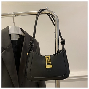 Dettaglio borsa nera in pelle con fibbia geometrica dorata e tracolla con nodo decorativo