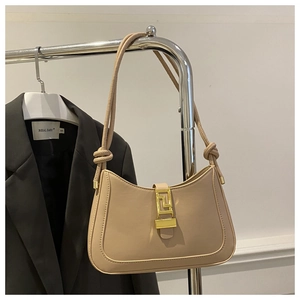 Dettaglio borsa a spalla beige con fibbia geometrica dorata e cinturino annodato