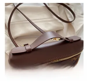 Détail du sac bandoulière léopard avec poignée en cuir marron et fermeture à glissière en métal