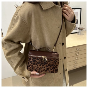 Détail du sac bandoulière à motif léopard avec rabat en cuir brun et zip doré