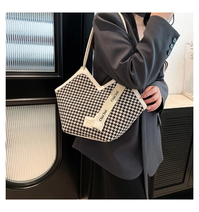 Close-up of houndstooth tote bag with V-shaped opening and stylish logo webbing details
