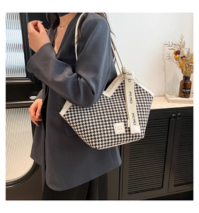 Detail shot of houndstooth tote bag featuring fashion label and lettered strap detail