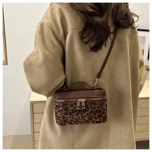 Détail du sac bandoulière léopard avec rabat en cuir marron et finitions dorées