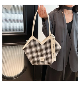 Detailed macro view of houndstooth fabric tote with leather trim and fashion ribbon charm