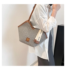Detail of houndstooth tote bag with brown leather trim and decorative canvas straps
