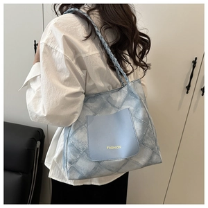 Dettaglio della borsa tote in denim azzurro con cuciture trapuntate e tracolla intrecciata