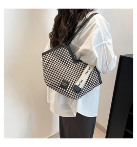 Close-up of houndstooth tote bag featuring a branded label and wide canvas strap