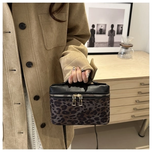 Détail du sac à bandoulière léopard avec fermetures éclair dorées et poignée en cuir noir