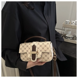 Detail of vintage square handbag with brown clover pattern and gold buckle on black shirt