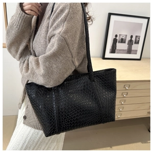 Detail of black woven leather tote bag showing large capacity and intricate texture
