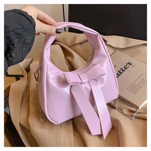Detail of pink patent leather handbag with oversized bow and silver chain strap