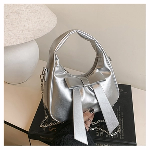 Close-up of metallic silver bucket bag with large bow detail and chain strap