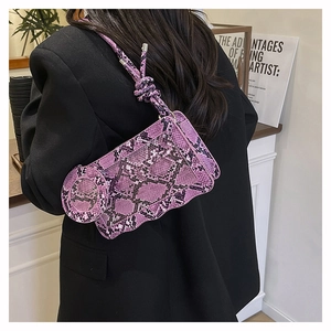 Detail of purple snakeskin crossbody bag with unique wavy edges and knotted shoulder strap