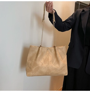 Détail d'un sac cabas kaki avec texture mate, rivets métalliques et chaîne dorée