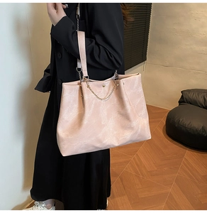 Detailed view of pink large tote bag with textured surface and stylish metal chain strap