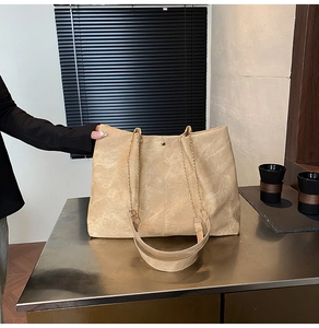 Detail der beigen Shopper-Tasche mit weicher Textur und goldener Kette für den Alltag