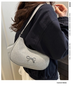Detail of silver sequin shoulder bag featuring a metallic bow and sparkling texture