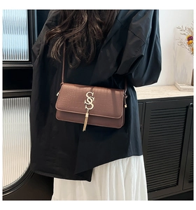 Detailed view of crocodile pattern leather shoulder bag with gold S logo and tassel fringe
