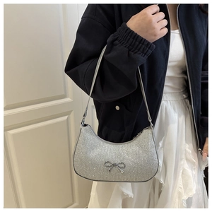 Detail of silver sequined hobo bag with metal bow accent shown on model shoulder