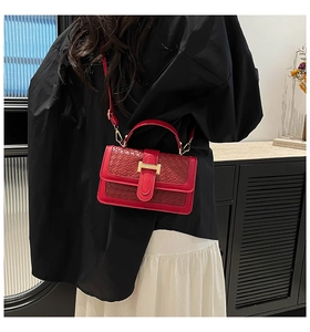 Detail of red straw woven bag with gold H-buckle on model wearing white dress