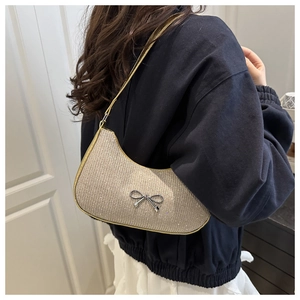 Detailed view of silver rhinestones and metal bow on a fashion shoulder bag
