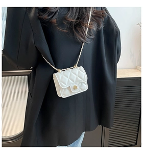 Close-up of white quilted mini crossbody bag with golden camellia lock and chain strap