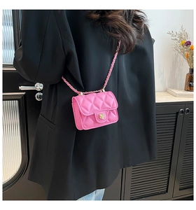 Close-up of quilted hot pink mini crossbody bag with gold floral clasp and chain strap