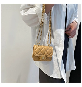 Close-up of caramel quilted mini bag with gold camellia lock and chain strap on model