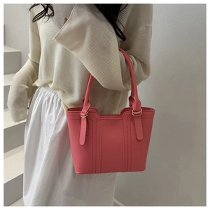 Detailed view of pink leather tote featuring vertical stitching and golden metal hardware