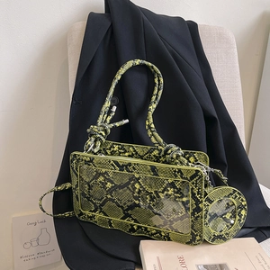 Neon green snake print crossbody bag with PVC slot on a black blazer backdrop
