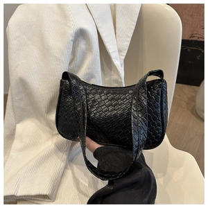 Gros plan sur la texture en cuir tressé noir et la poignée élégante de ce sac à main